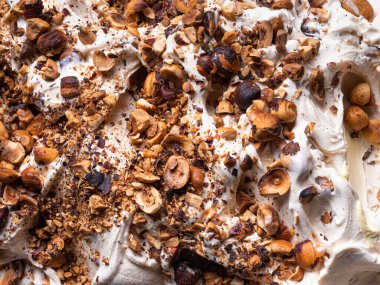 Donmuş fındık aromalı dondurma, tam çerçeve detay. Fındık parçalarıyla kaplı beyaz kremalı dondurmanın yüzey dokusunu kapat..