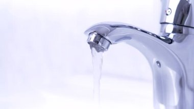 Water tap, stainless steel faucet in 4K VIDEO. Water flow in bathroom with sink. Modern clean house interior. Hygiene,  resources consumption and climate change concept.