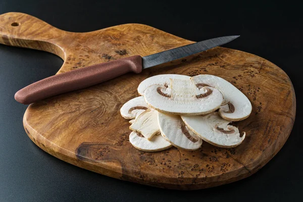 Champignon mantar ve ahşap kesme tahtası üzerinde bir bıçak