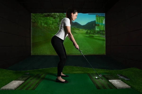 Ekran golfü oynayan bir kız. Golf Simülatörü.