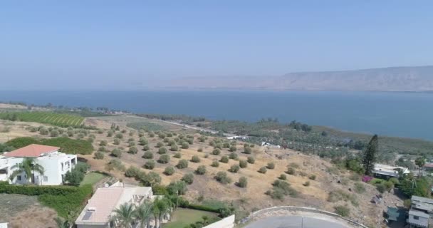 Golan Tepeleri ve Tiberias 'ın yukarısında gün batımında Celile Denizi ya da İsrail' in kuzeyindeki Ürdün Vadisi 'nde Kinneret ile hava görüntüleri. Turuncu yeşil manzaralı ve berrak dağlı açık arazilerin üzerinde insansız hava aracı — Stok video