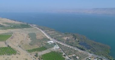 Golan Tepeleri ve Tiberias 'ın yukarısında gün batımında Celile Denizi ya da İsrail' in kuzeyindeki Ürdün Vadisi 'nde Kinneret ile hava görüntüleri. Turuncu yeşil manzaralı ve berrak dağlı açık arazilerin üzerinde insansız hava aracı
