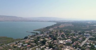 Golan Tepeleri ve Tiberias 'ın yukarısında gün batımında Celile Denizi ya da İsrail' in kuzeyindeki Ürdün Vadisi 'nde Kinneret ile hava görüntüleri. Turuncu yeşil manzaralı ve berrak dağlı açık arazilerin üzerinde insansız hava aracı