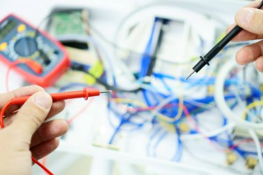 Usta, hatalı dişçi koltuğundaki elektrik devresini test cihazıyla kontrol ediyor. Tıbbi teçhizat onarımı.