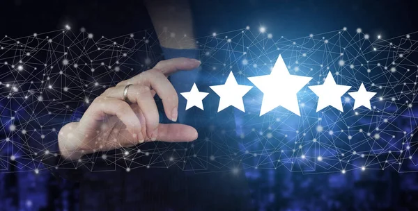İnceleme, Derecelendirme, Memnuniyet. El ele tutuşan dijital hologram şehrin karanlık arka planında beş yıldızlı işaret. Ürün hizmeti değerlendirme kavramı