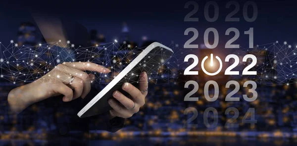 Yıl 2021 'den 2022' ye yükleniyor. Konsepte başla. Şehrin karanlık arka planında dijital hologram 2022 işareti olan beyaz tablete dokun. 2022 yılına hoş geldiniz..