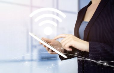 Kablosuz internet kavramı. El teması beyaz tablet, dijital hologram Wi-Fi yazısıyla bulanık arka planda. Şehirdeki iş ağı bağlantı kavramı ve Wi-Fi