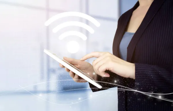 Kablosuz internet kavramı. El teması beyaz tablet, dijital hologram Wi-Fi yazısıyla bulanık arka planda. Şehirdeki iş ağı bağlantı kavramı ve Wi-Fi
