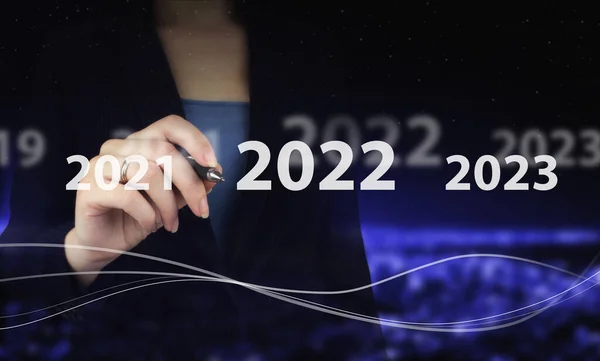 Yıl 2021 'den 2022' ye yükleniyor. Konsepte başla. Dijital grafik kalemle el ele tutuşmak ve şehrin karanlığına 2022 yazısını çizmek bulanıklaştırdı. Görüş 2021-2022 için kavram. İş adamına hoşgeldin yılı.