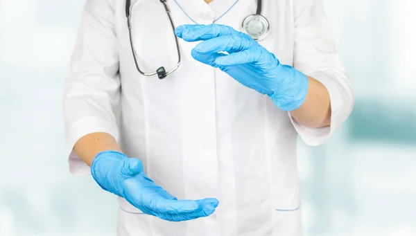 Doktor ürün ya da metin için kopyalama alanı sunuyor ve gösteriyor. Kadın doktor elinde tıbbi eldivenlerle bir şey gösteriyor..