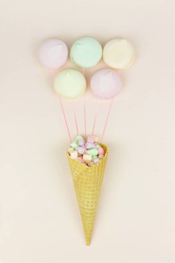 Yeşil, pembe ve sarı marşmelovlu sarı waffle külahı pastel arka planda badem kurabiyesi gibi görünüyor.