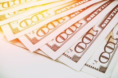 100 dolarlık Amerikan banknotları. Beyaz arka planda gün ışığıyla yerleştirilmiş 100 dolarlık banknotlar.