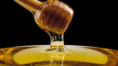 siyah arka plan üzerinde ahşap dipper bal damlama
