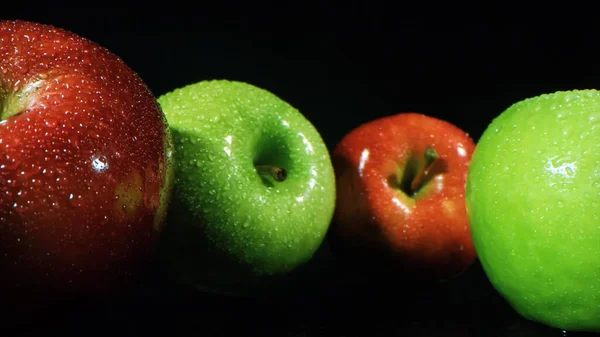 Green and red apples on black background