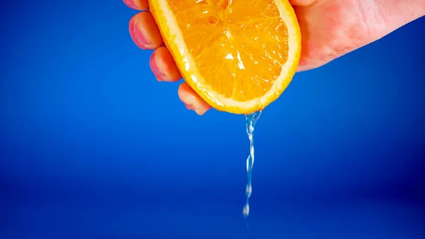 Hand Drückt Die Hälfte Der Zitrone Auf Einen Blauen Hintergrund — Stockfoto