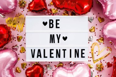 Stylish text frame with the inscription be my valentine. Pink, red and gold hearts all around. Foil balloons top view of Valentine's Day. Copyspace.