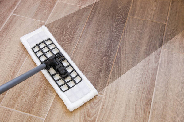 Washes wood brown floor with mop and white wet rag. 