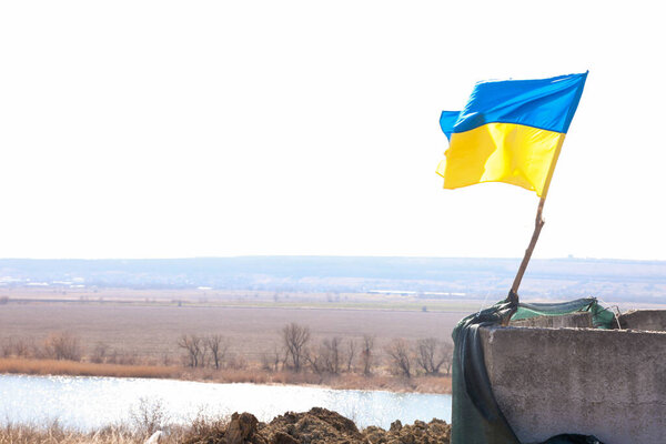 Flag of Ukraine at the checkpoint. Spring landscape. War in Ukraine.