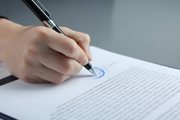 рука женщины подписывает документ крупным планом. Подписание контракта. Подпись