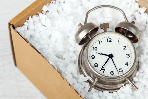 beautiful wind-up alarm clock in package with styrofoam on white wooden background