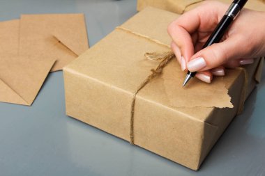 Kadın, gri ahşap arka plandaki paketin etiketini imzaladı.