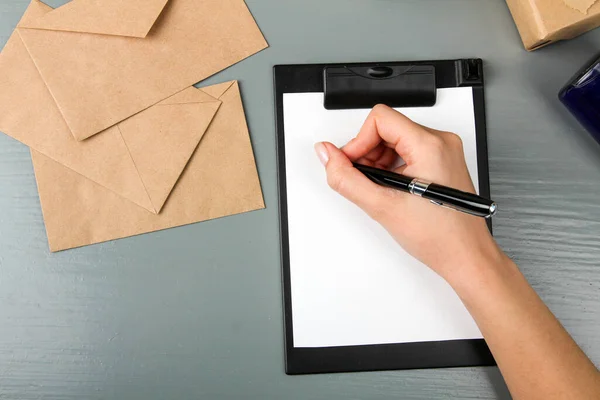 Mão Mulher Escreve Papel Sobre Fundo Madeira Cinza Envelopes Artesanato — Fotografia de Stock