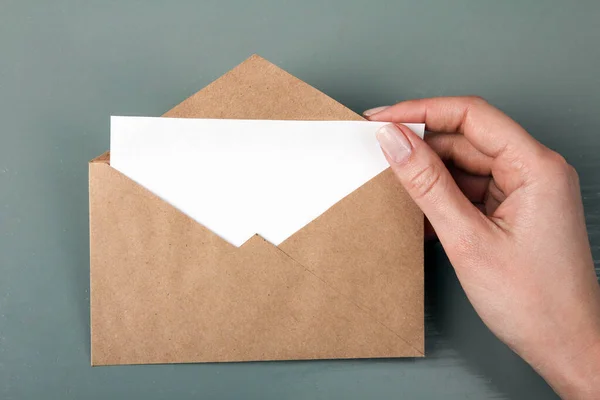 woman takes out letter from envelope on gray wooden background