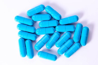 Lot of blue medicine capsules on white background. Dietary supplement.