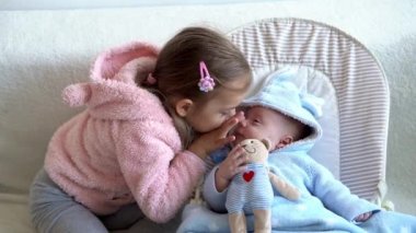 Arkadaşlık, aile, bebek, çocukluk iki küçük gülümseme bebek yatakta oyuncak ayıyla oynarken rahatlıyor. Büyük abla kendine iyi bak küçük kardeş evde karantinada iyi eğlen, mutlu çocuklar.