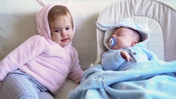 우정, 가족, 유아, 어린 시절의 개념 - 귀여운 미소를 짓는 귀여운 아기 두 명 이 부드러운 침대에서 노는 것을 편안하게 해준다. 쌍둥이 쌍둥이 동생은 격리 구역에서 재미있고 행복 한 아이들을 만난다 — 비디오