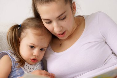 Mutlu aile, genç anne, bebek bakıcısı, kitap oku, rahatla, küçük kızları kucakla, gülümse anne, küçük çocuklara masal anlat, kanepeye otur, evde birlikte eğlenelim.