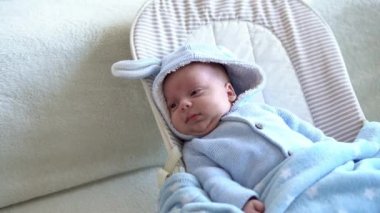 Kameradaki bebeğe bak. Yakın çekim. bebek, çocukluk, ebeveyn sevgisi, duygusal konsept - kahverengi gözlü tombul bebeğin sevimli gülen yüzü yumuşak mavi ceketli bebek uyanık yatağında yatıp etrafına bakıyor