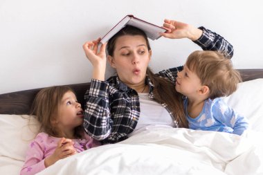 Mutlu bir aile. Sevgi dolu bir anne kızıyla birlikte yatıyor iki çocuk pijamaları yatakta ilginç hikayeler okuyor, anaokulunda gülümseyen kız çocuk masalların keyfini çıkarıyor.