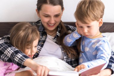 Mutlu bir aile. Sevgi dolu bir anne kızıyla birlikte yatıyor iki çocuk pijamaları yatakta ilginç hikayeler okuyor, anaokulunda gülümseyen bir kız çocuk peri masalının tadını çıkarıyor.