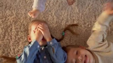 Arkadaşlık, aile, oyun konseptleri iki gülümseyen okul, yeni yürümeye başlayan çocuklar. Gülen savaş kardeşleri yerde yatan küçük ikizler kameraya bakın, mutlu çocuklar evde karantinada.