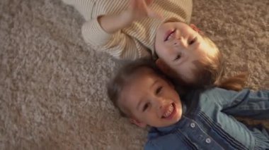 Arkadaşlık, aile, oyun konseptleri iki gülümseyen okul, yeni yürümeye başlayan çocuklar. Gülen savaş kardeşleri yerde yatan küçük ikizler kameraya bakın, mutlu çocuklar evde karantinada.