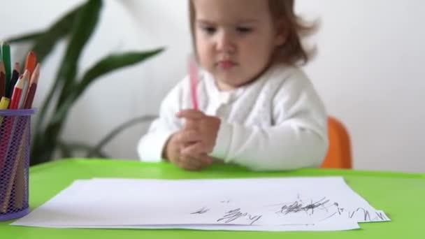 Närbild kaukasiska lilla barn dotter glad rolig unge lockigt liten flicka med ritningar bild vid bordet. koncentrerad kreativ småbarn skriver med färgade pennor på papper barnrum. hobbystudier hemma — Stockvideo