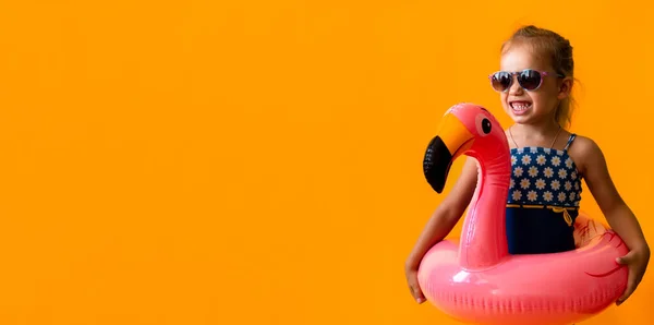 Banner šťastný malý dítě plavec sport dítě dívka nosit sluneční brýle plavky, Kid Nafukovací plavecký kroužek Pink Flamingo, izolované oranžové pozadí, horké letní prázdniny hobby koncept. Kopírovat mezeru — Stock fotografie