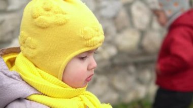 Avrupalı küçük çocuğun portresi. Pis çocuk grl sarı örgü şapka gri ceketli. Kameraya gülümsüyor. Duygusal olarak gülen çocuk gülen, poz veren, gülen eller, Autumn 'un dışı.