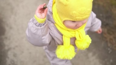 Bebek rünü. Gri tulumlu, sarı şapkalı küçük kız orman yolunda yürüyor. Çocuk komik bir aile hayali kuruyor. Yeni yürümeye başlayan çocuk dışarıda. neşeli mutlu çocukluk tasasız çocuklar bahçede yürür