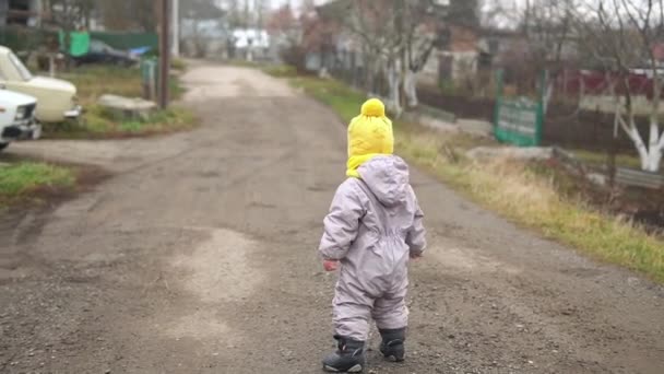 Baby runing. little girl in grey jumpsuit yellow hat walking through forest park path. kid dream funny family concept. Toddler outside. fun happy childhood carefree Children walk child in yard — Stock Video