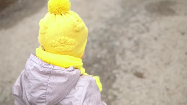 Bebek rünü. Gri tulumlu, sarı şapkalı küçük kız orman yolunda yürüyor. Çocuk komik bir aile hayali kuruyor. Yeni yürümeye başlayan çocuk dışarıda. neşeli mutlu çocukluk tasasız çocuklar bahçede yürür — Stok video
