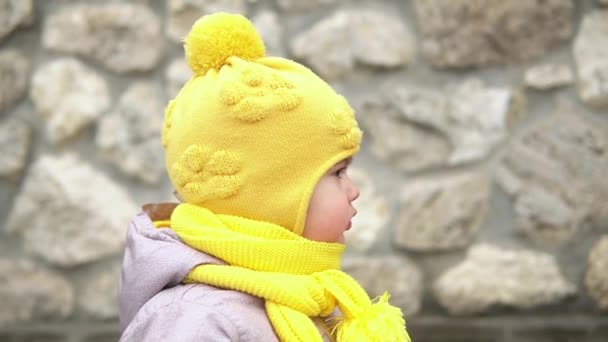 Zbliżenie Portret europejskiego maluszka brudne biedne dziecko grl w żółtej dzianiny kapelusz szara kurtka uśmiechnięty spojrzeć w aparat fotograficzny. Emocjonalnie dziecko śmieje się uśmiechnięte, pozujące na okładce oczy ręce przed jesienią — Wideo stockowe