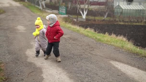 Runing.Dwójka małych dzieci w szarym kombinezonie w żółtym kapeluszu spacerująca ścieżką leśnego parku. Dzieciak marzy o zabawnej rodzinie. Rodzeństwo na zewnątrz. zabawa szczęśliwy dzieciństwo beztroskie dzieci chłopiec dziewczyna spacer w podwórku — Wideo stockowe
