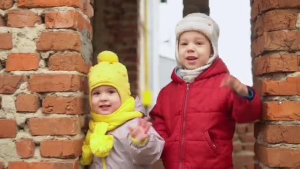 Baby runing.Two little kids in grey jumpsuit yellow hat walking through forest park path. kid dream funny family concept. Siblings outside. fun happy childhood carefree Children boy girl walk in yard — Stock Video