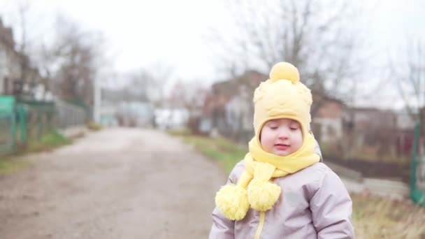 Dziecko rusza. Dziewczynka w szarym kombinezonie w żółtym kapeluszu spacerująca ścieżką leśnego parku. Dzieciak marzy o zabawnej rodzinie. Maluch na zewnątrz. zabawa szczęśliwy dzieciństwo beztroskie dzieci spacer dziecko w podwórku — Wideo stockowe