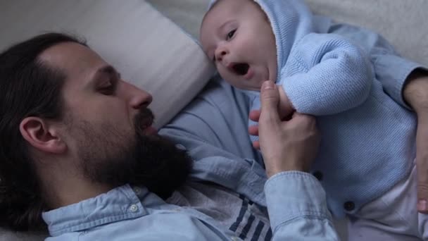 Cinematic Shot Bearded langharige jonge neo vader spelen met pasgeboren baby in de kinderkamer thuis. Papa ligt met een kind te slapen. Kinderen, Ouderschap, Jeugd, Leven, Liefde, Vaderschap, Familie Concept — Stockvideo