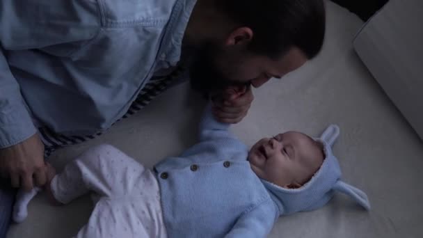 Auténtico barbudo de pelo largo joven Neo padre y bebé recién nacido mirando el uno al otro sonriendo en la cama. Papá acostado con un bebé. Hijos, Parentalidad, Infancia, Vida, Amor, Padres, Concepto Familiar — Vídeos de Stock