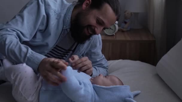 Authentic Happy Bearded Long-haired Young Neo Father And Newborn Baby Holding Hand Smiling On Bed. Dad Laying With Infant Child. Children, Parenthood, Childhood, Life, Love, Fatherhood, Family Concept — Video Stock