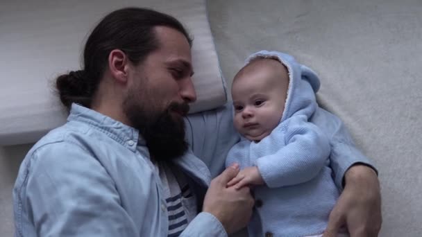 Cinematic Shot Bearded Long-haired Young Neo Father Smiling With Newborn Baby In Nursery At Home. Dad Laying With Infant Child. Children, Parenthood, Childhood, Life, Love, Fatherhood, Family Concept — 图库视频影像